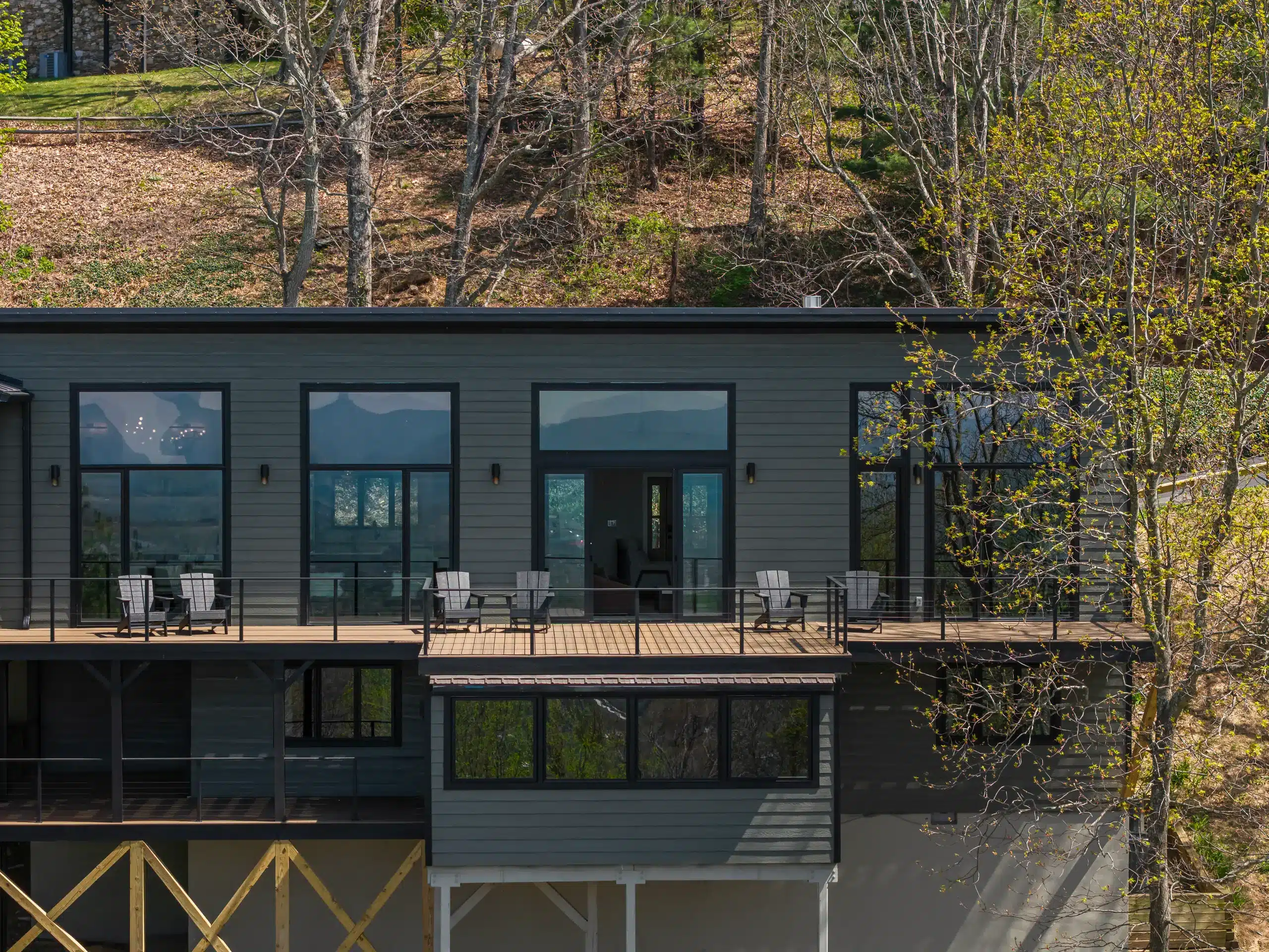 Luxury modern mountain home exterior with wood deck and black-framed windows, Asheville NC